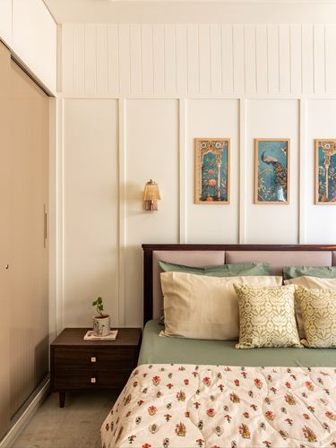 Bedroom with panelled wall, peacock artwork, upholstered headboard and green bedding beside a sliding wardrobe