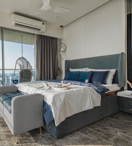 Contemporary bedroom with blue wingback bed, city view balcony and hanging swing chair