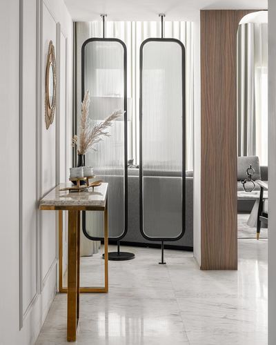 Marble-floored foyer with brass console, gold mirror, and two tall ribbed glass floor mirrors leading to living room