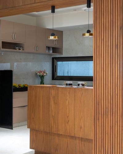 Kitchen island in wood veneer framed by fluted wood partition, brass pendant lights above