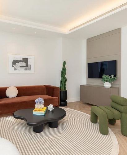 Living room with terracotta velvet sofa, green boucle chair, and cloud-shaped black coffee table on geometric rug