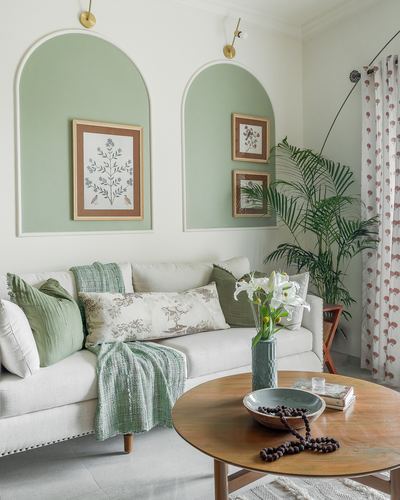 Living room with sage green arched wall niches, white sofa with green cushions, round wooden coffee table