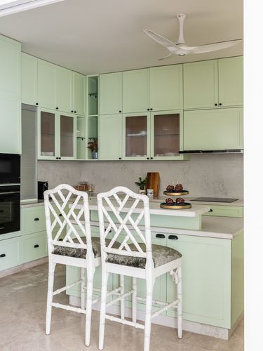 Mint green kitchen with white fretwork bar stools and stone countertop island