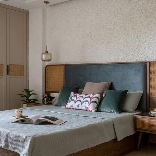 Bedroom with cane and upholstered headboard, cane nightstands, textured plaster wall and pendant light