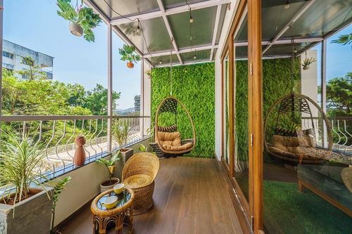 Balcony with hanging rattan chairs against a green wall and wooden flooring, mirrored on one side