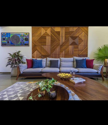 Living room with grey sofa, patterned wood wall panel, and curved wooden coffee table