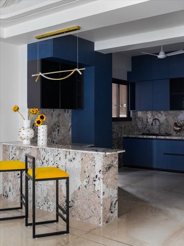 Navy blue kitchen with patterned stone breakfast counter and yellow bar stools