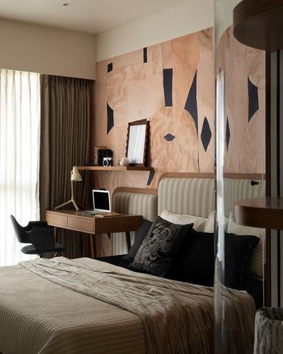 Bedroom with striped headboard, abstract terracotta wall art, and built-in study desk beside curtained window