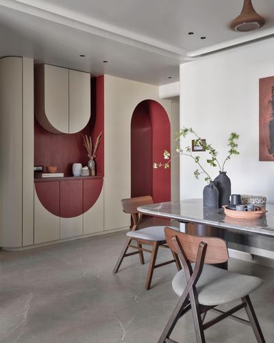Dining nook with maroon arched cabinetry, curved doorway, and marble table with wooden chairs