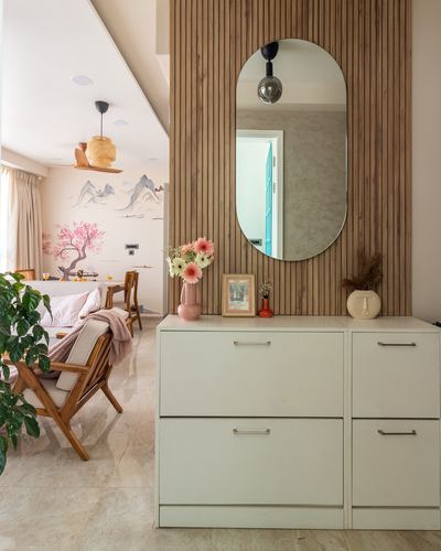 Foyer with wood slat wall, oval mirror, and cream storage cabinets, living room beyond