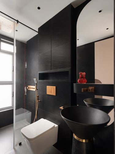Black stone bathroom with two conical basins, arched mirror, and wall-hung toilet