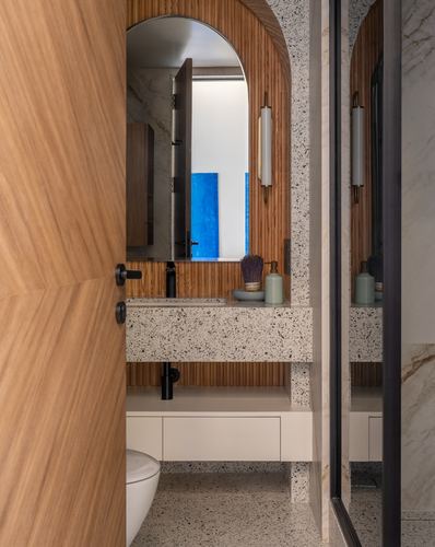Bathroom with arched wood niche, terrazzo counter, and open wooden door in foreground