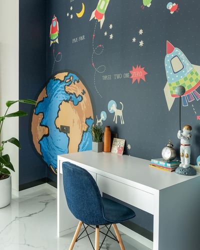 Kids study desk against navy space-themed mural wallpaper with blue chair