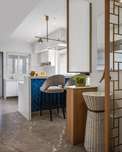 Kitchen island with blue herringbone tile, marble floor, and brass jali screen partition