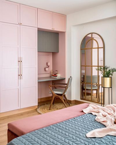 Pink bedroom with wardrobe, study nook, arched brass mirror and blue-pink bedding