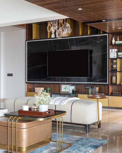 Living room with black marble TV wall, mustard shelving, cream bench and wooden brass coffee table
