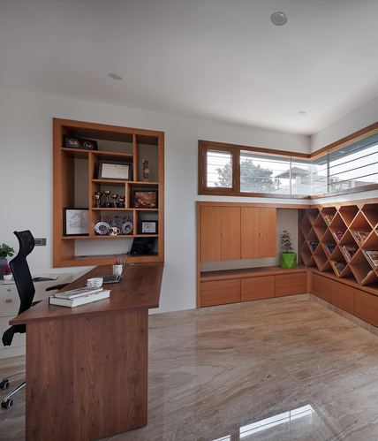 Wood-paneled home study with built-in desk, display shelves, and diamond-pattern corner bookshelf