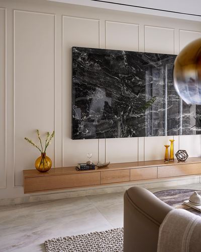 Floating wood console beneath a large dark stone panel on a paneled cream wall