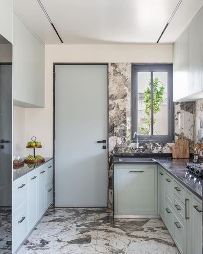 Sage green U-shaped kitchen with dark countertop and dramatic marble backsplash wall