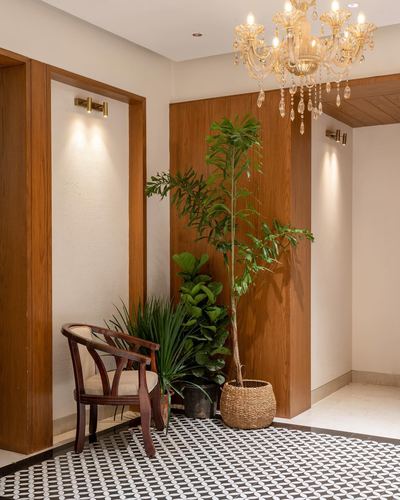 Entryway with wood paneling, chandelier, plants, cane chair, and patterned black-white floor tile