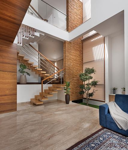 Double-height foyer with floating wood staircase, stone column, marble floor and blue sofa