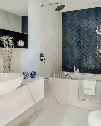 Marble bathroom with white vessel sink, freestanding tub, and blue herringbone tile accent wall