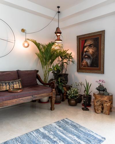 Living room corner with wooden bench, potted plants, framed portrait, and pendant lights over marble floor