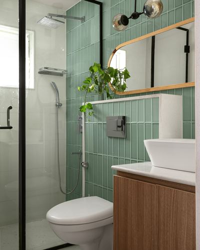 Bathroom with green tiled walls, glass shower, wood vanity and arched wooden mirror