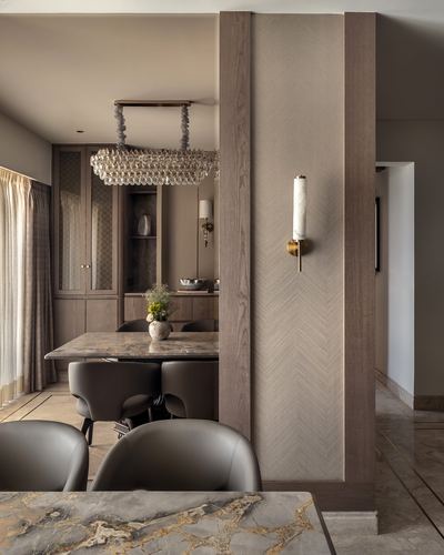 Dining room with stone-top table, leather chairs, fluted wood pillar and marble sconce