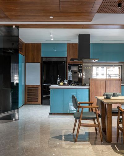 Teal and wood kitchen with island, chimney hood and adjoining wooden dining table