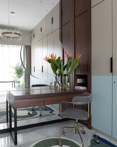 Study nook with wooden desk, round mirror, brass chair and marble floor in neutral toned apartment