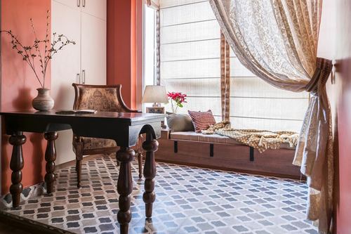 Rustic study nook with carved desk, patterned tile floor and curtained window seat