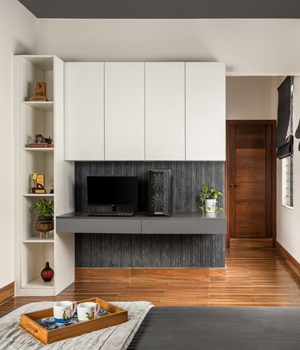 White cabinetry over grey desk with fluted panel backdrop and monitor in bedroom study nook