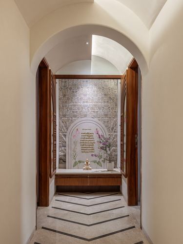 Arched hallway leading to a small temple niche with brass idol against a patterned wall