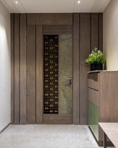 Wood-panelled entrance door with vertical stone insert and plant beside console table
