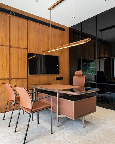 Wood-paneled office with leather desk, tan chairs, and sculptural pendant light