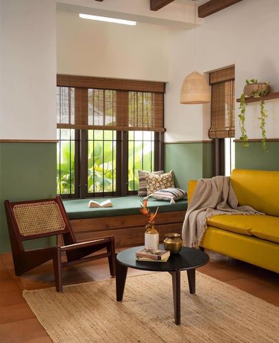 Living room with green window seat, yellow sofa, cane chair and round black coffee table