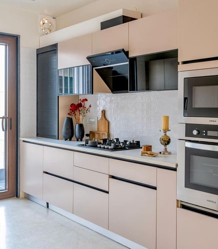 Blush pink modular kitchen with black chimney hood, hexagonal tile backsplash, and stainless steel built-in ovens