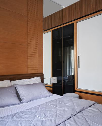 Bedroom with wood-panelled wall, grey bedding, and a wardrobe with mirrored and dark glass panels