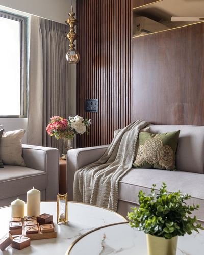 Living room corner with fluted wood wall, brass pendant, grey sofas and marble coffee table