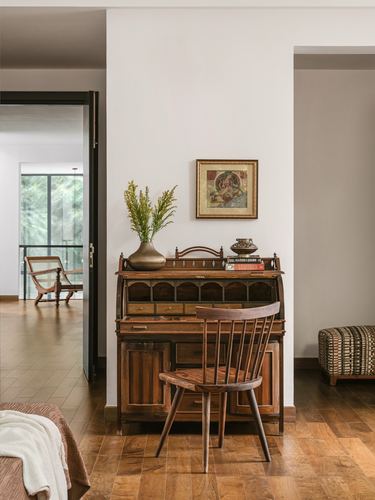 Wooden roll-top desk with windsor chair and framed art in a hallway nook