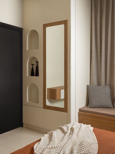 Beige foyer with arched niches, wood-framed mirror, cabinetry, bench and orange rug