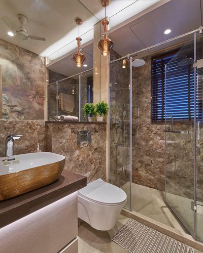 Marble bathroom with vessel sink, glass shower, and hanging copper pendant lights