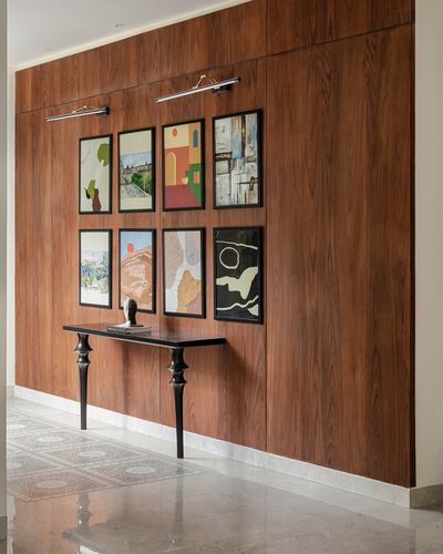 Wood-paneled foyer wall with gallery of framed art above a black console table
