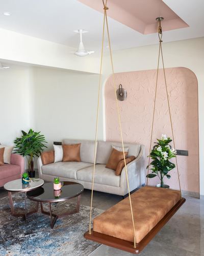 Living room with a hanging leather swing in front of a pink textured arched wall niche