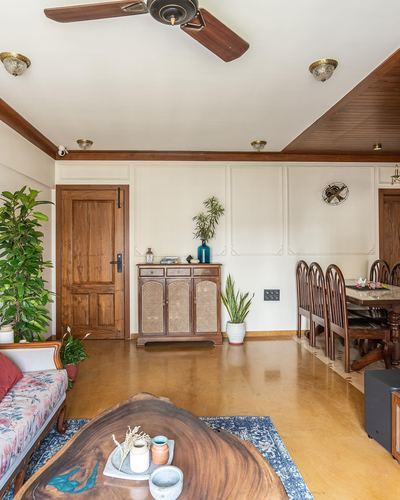 Living and dining space with wood ceiling, cane cabinet, live-edge table and molded white walls