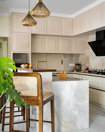 Cream cabinetry kitchen with marble waterfall island and cane bar stools