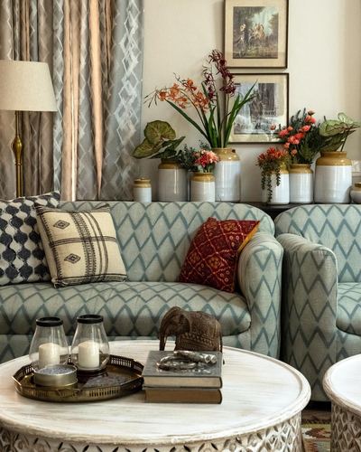 Living room sofa with patterned cushions, carved coffee table, and ceramic jars with flowers behind