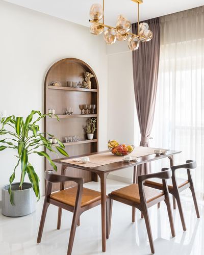 Wooden dining table with leather chairs beside an arched wood shelving niche and sheer curtains