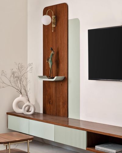 Wood and mint arched panel with brass sconce and figurine above a floating TV console